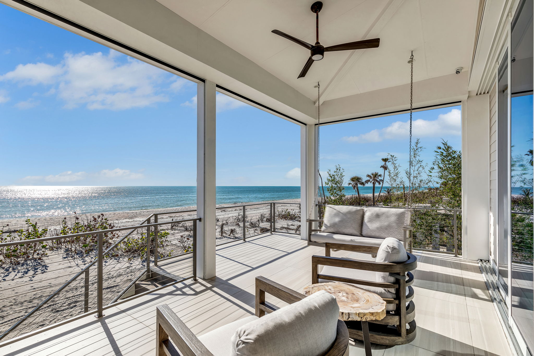 The beachfront porch and furniture blend seamlessly with the surrounding beach