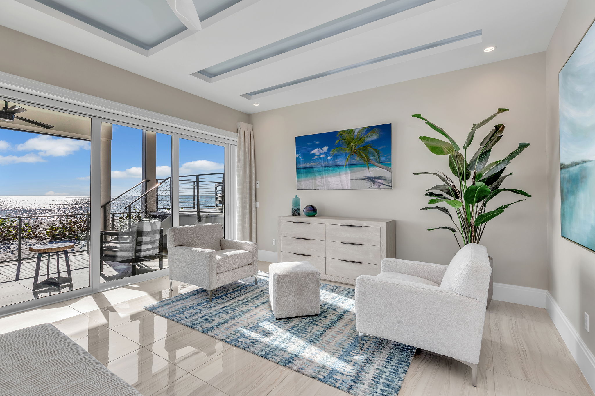 Paintings and an area rug add splashes of aqua and blue to the sitting area of the master bedroom