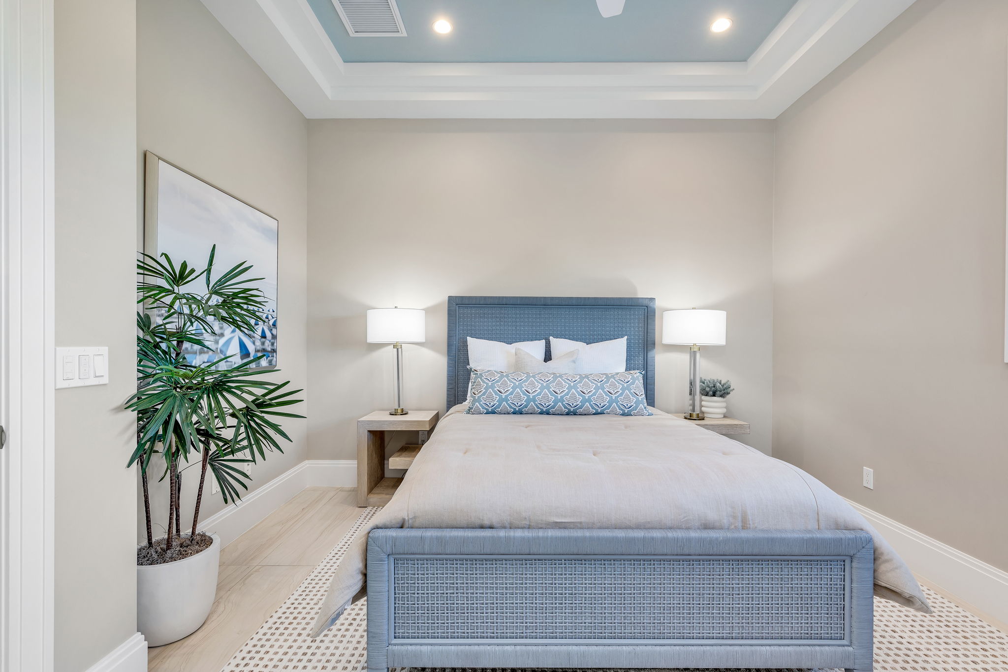 The headboard, footboard, and pillows incorporate soft blues, while faux plants add touches of green and a hint of nature