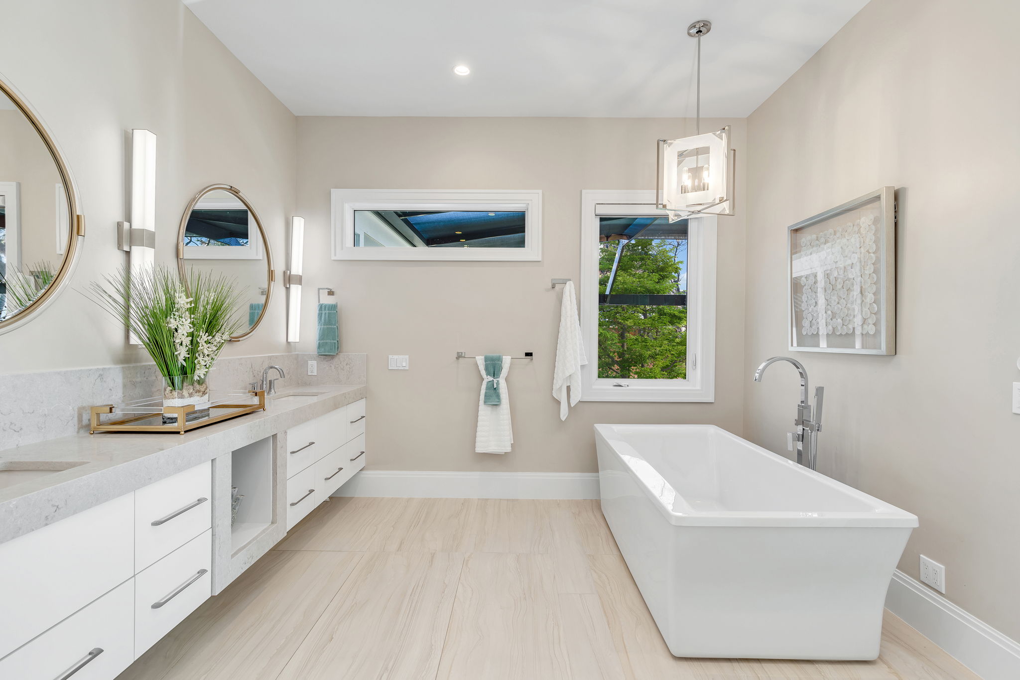 The spacious master bath features mostly sand-toned materials, with towels and decor adding splashes of blue and green